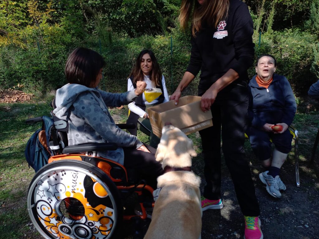 Ragazza su sedia a rotelle con il cane di fianco e l'assistente